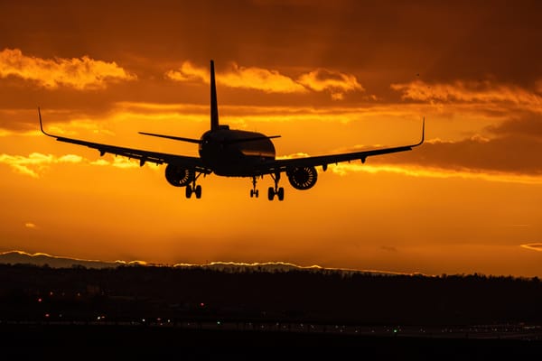 An airplane taking off from the runway during golden hour with a mountain range in the background.